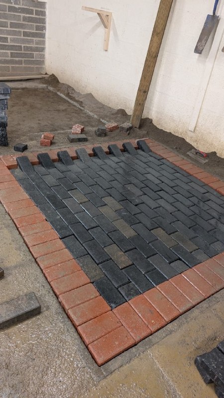 Partially completed herringbone brick patio installation with red brick border in Newcastle