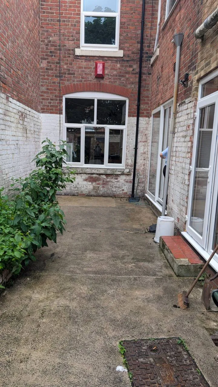 Original enclosed outdoor area with worn concrete and weathered brick walls