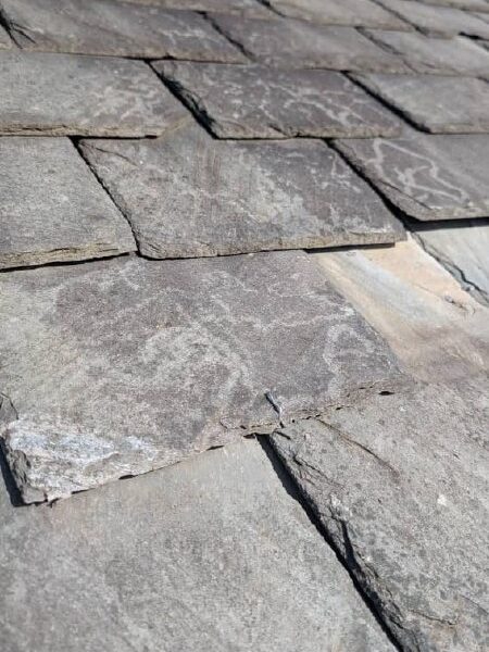 Damaged slate tiles identified during a roof inspection