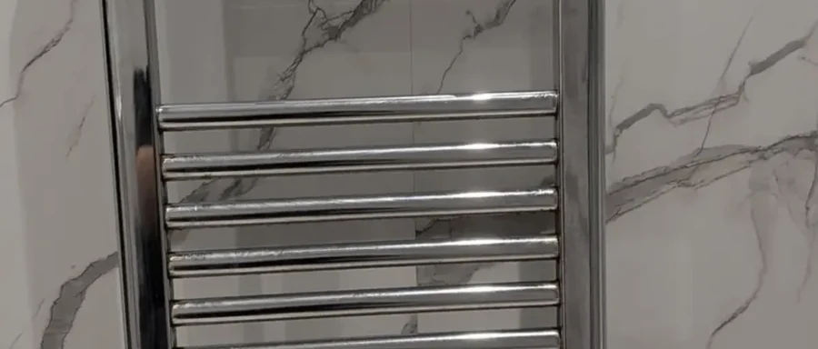 Chrome towel radiator fitted to a tiled bathroom wall near Newcastle