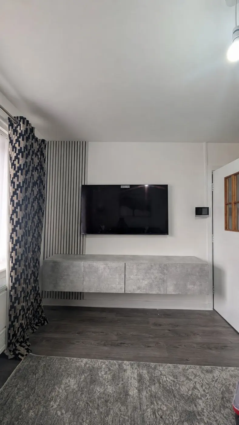 Wall-mounted television above a floating media unit and slatted wall panel