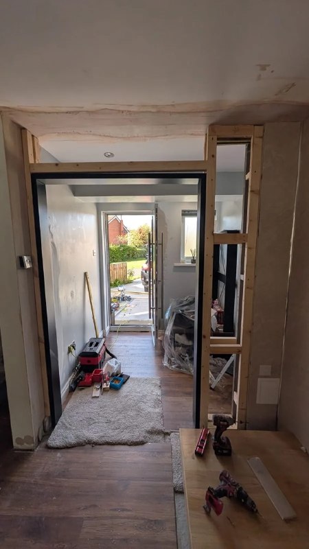 Timber framing built around a black glazed double door frame